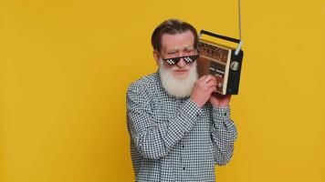Senior old man using retro tape record player to listen music, disco dancing favorite track, having fun, entertaining, fan of vintage technologies. Elderly grandfather pensioner on yellow background video