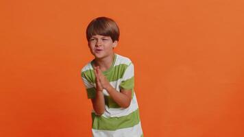 Please, God help. Preteen child boy kid praying making wish, asking with hopeful imploring expression, begging apology, asks not to punish him for bad behavior. Little children on orange background video