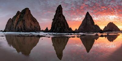 Sunset Beach Scene with Four Rock Formations Reflecting in Calm Water photo