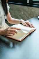 A woman turns pages of a notebook while seated at a desk, capturing a moment of focus and productivity. photo