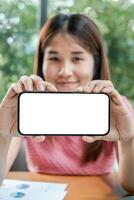 Woman displaying a smartphone with a blank screen, ideal for mockup or design purposes, in an office environment. photo