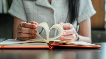 Close-up of hands forming a heart shape with book pages, symbolizing love for reading and literature. photo