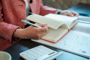 Close-up of a person writing in a planner with a calculator, focusing on financial planning and organization. photo