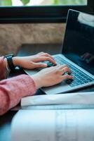 Hands typing on a laptop in a well-lit workspace, creating a productive and cozy atmosphere. photo