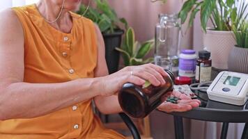An old woman pours a handful of green dietary supplement pills into her palm from a dark jar. video