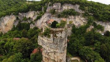 Drone aerial Katskhi Pillar limestone monolith with Orthodox monastery on top in Chiatura, Georgia. Unique spiritual site of ascetic hermit monks, dramatic cliff in lush green landscape video