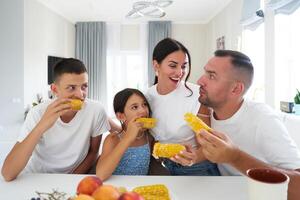 Family enjoying fresh corn on the cob at home during a sunny afternoon photo
