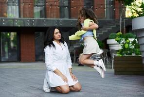 Mother and daughter playfully interacting outdoors in a modern urban setting during the day photo
