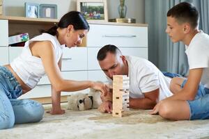 Family enjoying a game of Jenga on the living room floor in bright daylight photo