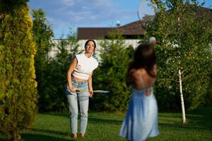 Woman and girl playing catch in a sunny backyard during late afternoon photo