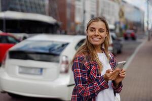 A young woman happily smiling while texting on her smartphone in an urban city setting photo