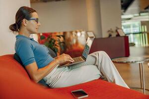 A professional woman is diligently working on her laptop in a modern workspace environment photo