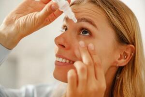 A woman is applying eye drops to achieve relief and hydration for her eyes comfort photo