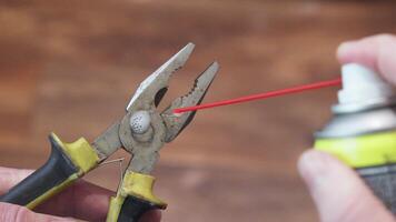 A hand lubricates pliers with a spray can, maintaining the working tools condition video