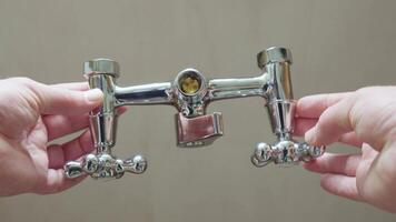 A water faucet mixer with two valves held in hands, showcasing its chrome finish video