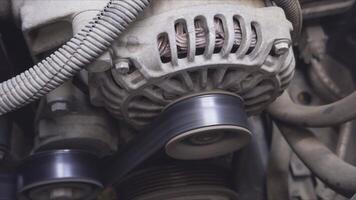 Operation of a car alternator with a rotating pulley and drive belt, showcasing an active process in the engine compartment video