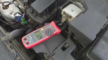 Current measurement in a car using clamp meters in the engine compartment, displaying values on a digital screen video