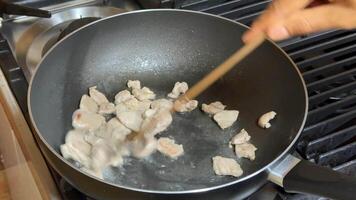 A person stirs diced chicken in a frying pan, highlighting cooking, culinary techniques, and home cooked meals video