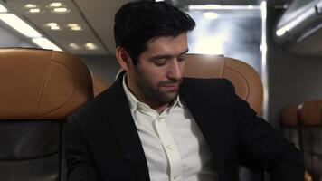 Businessman, in a suit travels on airplane working on a tablet and speaking on the phone video