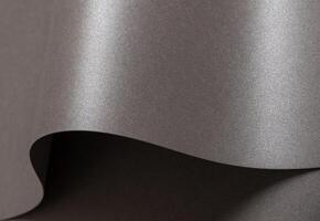 Gray glossy paper texture with a sleek, pearlescent finish, featuring wavy folds and edges. Elegant, photo