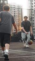 Older brother plays basketball with the younger one on the playground. He gives in to his younger brother, who takes the ball away from him during the game. Vertical. video