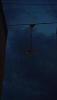 Boots suspended from cables are hung against backdrop of apartment buildings in particularly deprived part of city in dead of night. This tradition, known as shoefiti, points to dangerous place. video