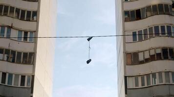 Sneakers suspended from wires hang between two apartment buildings in a decidedly poor area of the city. This street custom is called shoefiti. video