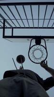 bottom view of a street basketball player throwing a ball into a basket from under the hoop. outdoor basketball court in the evening video