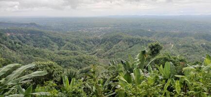 Lush Green Hilltop Panorama Stunning View of Distant Village and Rolling Hills photo