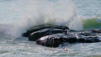 A wave crashes over a rock in the ocean video