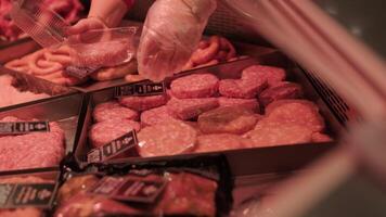 Butcher placing raw meat patties into plastic container at meat counter video