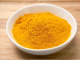 Aromatic spice in turmeric powder in a white cup on a wooden background. photo