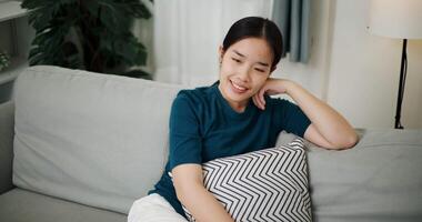 Handheld high angle view shot, Relaxed woman is sitting on a sofa, enjoying the peace of mind and seems to be thinking about something in a positive mood in living room at home. video