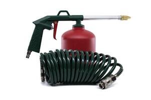 Close-up shot of an air-powered spray gun and its accessories against a white backdrop. photo