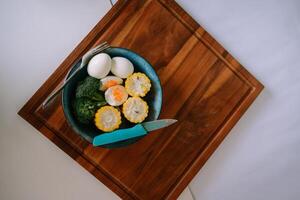 Healthy vegetarian breakfast with eggs, broccoli and corn on wood plate photo