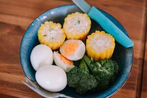 Colorful plate of nutritious food, eggs, corn, and broccoli ready to eat photo