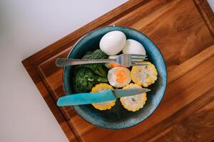 Nutritious plate with eggs, broccoli, and corn on a wooden board photo