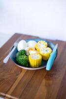 Healthy meal with broccoli, eggs, and corn on a wooden table photo