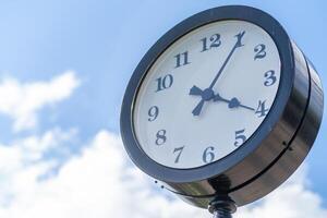 Vintage Clock on a Post Against a Blue Sky With Fluffy Clouds During Midday photo