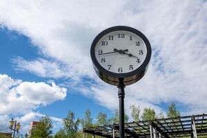 Decorative Outdoor Clock in a Park Setting Showing Mid-Afternoon Time Against a Backdrop of Clouds and Blue Sky photo