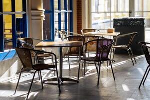 Cozy Cafe Interior With Wooden Tables and Wicker Chairs in Bright Natural Light During the Afternoon photo