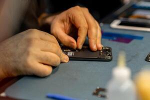 Expert Technician Repairing Phone at a Workspace With Tools and Components in a Well-Lit Environment photo