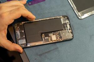 Phone Repair Technician Working on a Disassembled Device in a Workshop Setting During Daylight Hours photo