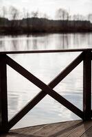 Wooden Railing Overlooking Calm Water Under Soft Cloudy Sky at Dawn photo