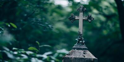 A weathered stone cross stands in a lush green cemetery with trees in the background and ivy growing photo