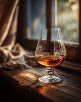 Elegant snifter glass filled with aged Armagnac on a rustic wooden table photo