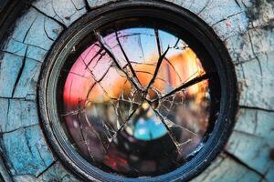 Cracked Camera Lens Capturing a Distorted Reflection of a Bustling Photography Marketplace photo