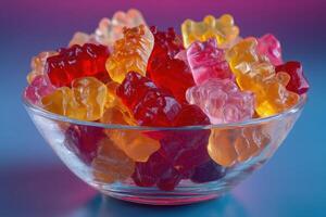 Gummy bears in a glass bowl on a blue background photo