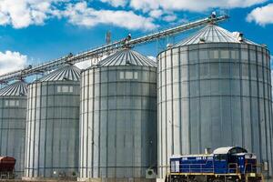 Metal tanks for storage of grain. Modern granary elevator. Loading and transportation of agricultural products by railway. photo