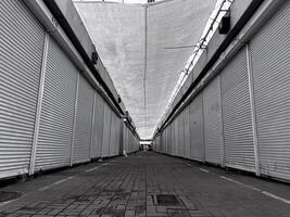 The empty market features countless closed stalls, their shutters down, as a soft light filters through the canopy above in the peaceful morning air photo